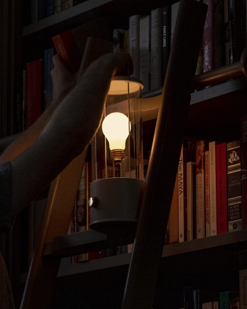 Warm glass lantern resting on a timber library ladder beside books