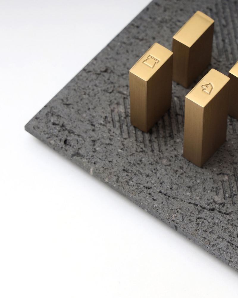 Pitted dark volcanic basalt tray with brushed brass sculptural blocks