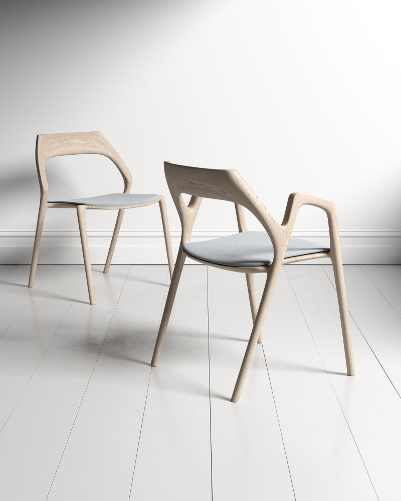 Pair of sculpted pale ash armchairs with muted stone seat pads on painted timber floorboards